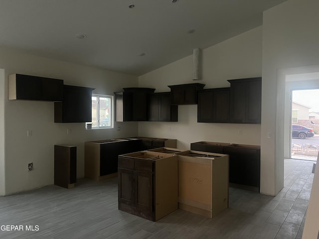 kitchen featuring high vaulted ceiling, light hardwood / wood-style floors, and a kitchen island