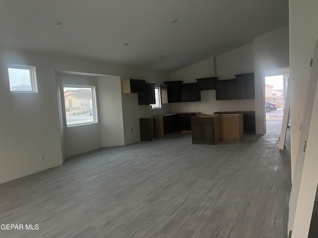 kitchen featuring lofted ceiling, a kitchen island, and light wood-type flooring