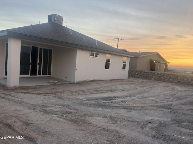 back house at dusk featuring central air condition unit and a patio