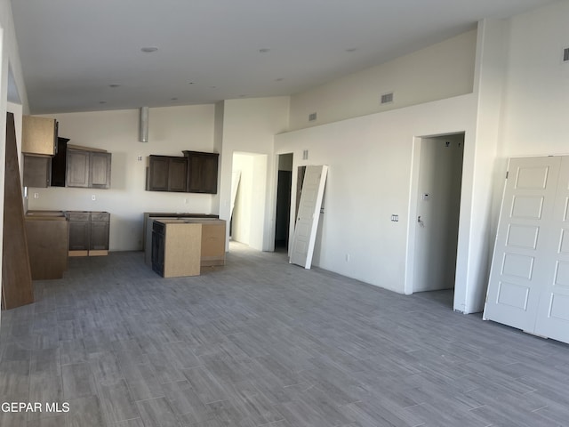 kitchen featuring a kitchen island, wood-type flooring, and a towering ceiling