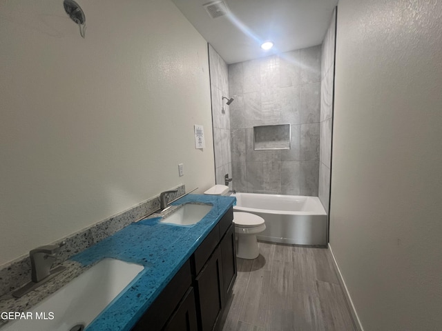 bathroom featuring toilet, wood finished floors, visible vents, and a sink