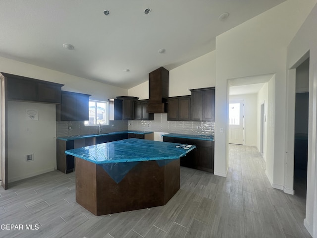 kitchen featuring a center island, wood tiled floor, dark brown cabinetry, vaulted ceiling, and custom exhaust hood