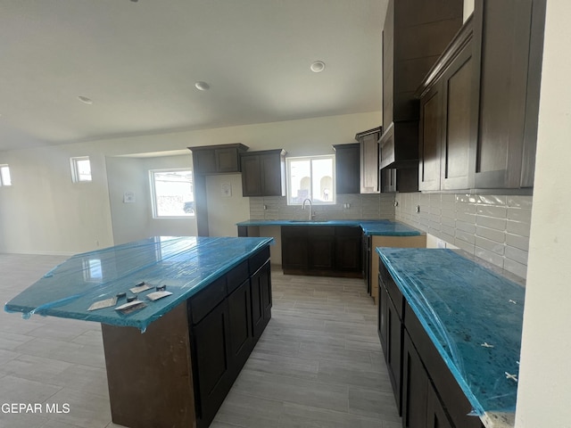 kitchen featuring tasteful backsplash, recessed lighting, a kitchen island, and a sink