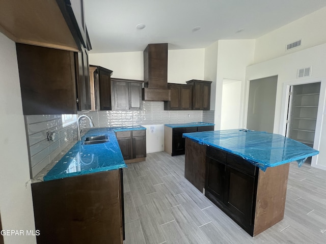 kitchen with a sink, visible vents, custom exhaust hood, and dark brown cabinets