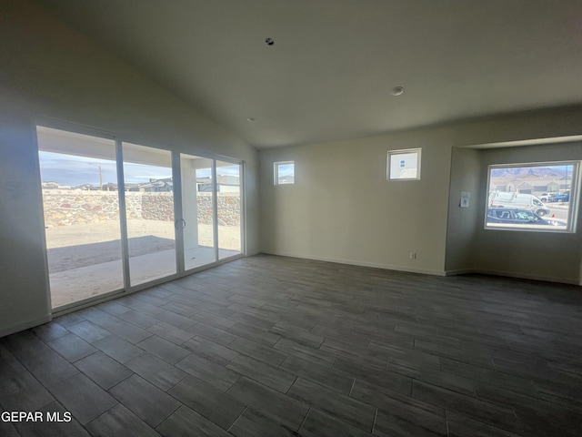 unfurnished room with baseboards, lofted ceiling, and dark wood-style flooring