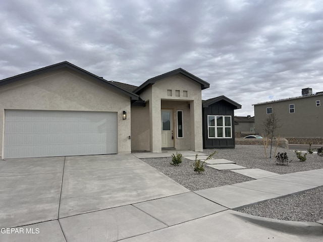 view of front of home with an attached garage, board and batten siding, driveway, and stucco siding