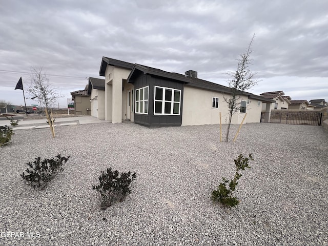 view of home's exterior with stucco siding, board and batten siding, and fence