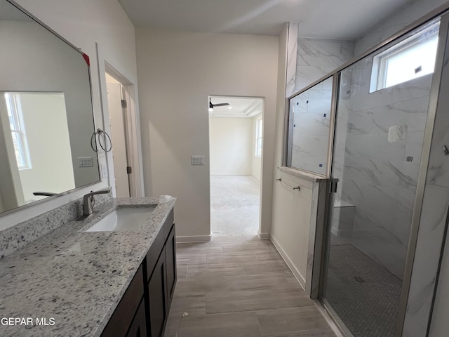 full bathroom featuring a marble finish shower, vanity, and baseboards