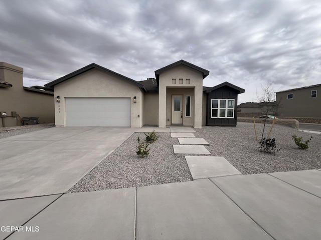 view of front of home with board and batten siding, a garage, driveway, and stucco siding