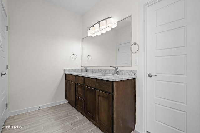 bathroom with double vanity, wood tiled floor, baseboards, and a sink