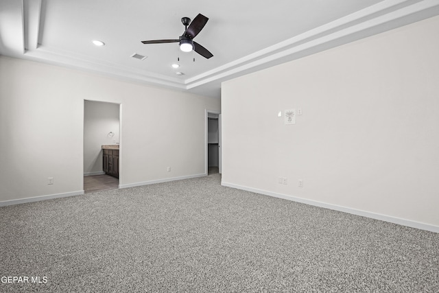 interior space featuring connected bathroom, a tray ceiling, baseboards, carpet floors, and recessed lighting