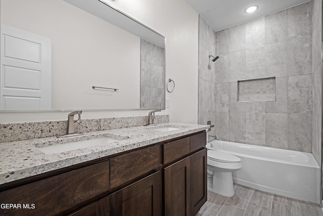 full bath with toilet, double vanity, a sink, and shower / bathing tub combination