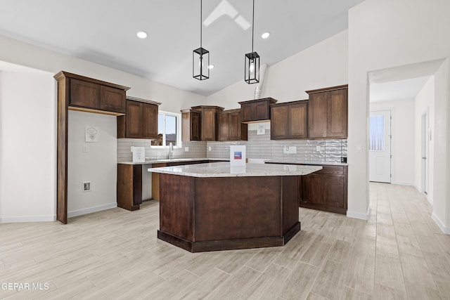 kitchen with dark brown cabinets, light wood-type flooring, decorative backsplash, and a center island