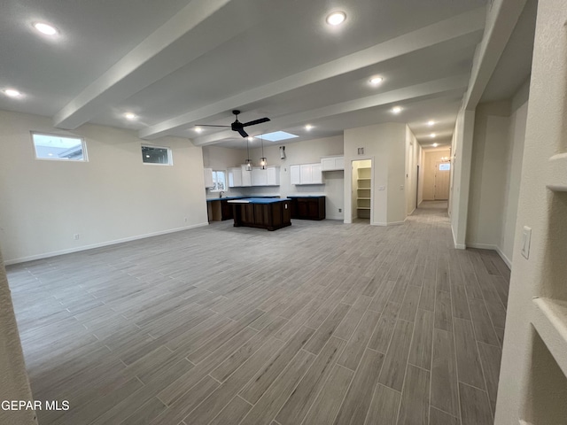 unfurnished living room with beam ceiling, light hardwood / wood-style floors, and ceiling fan