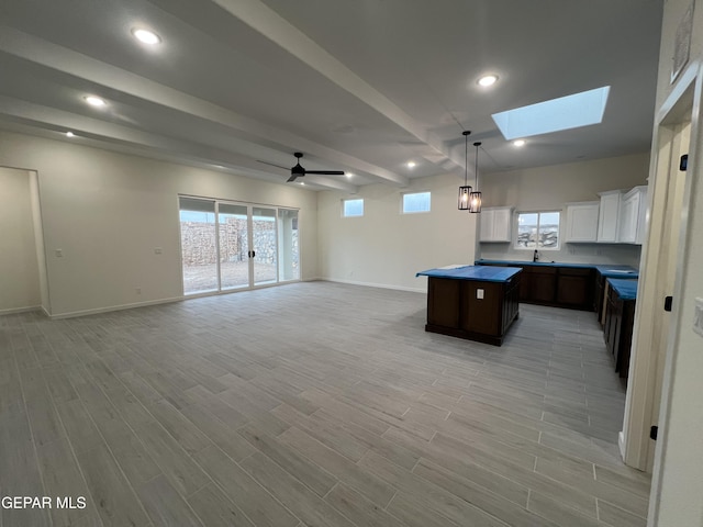 kitchen with dark brown cabinetry, white cabinetry, a center island, ceiling fan, and light hardwood / wood-style floors