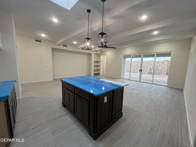 kitchen featuring beamed ceiling, pendant lighting, and a kitchen island