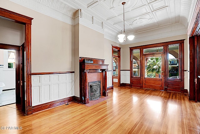 unfurnished living room featuring a notable chandelier, coffered ceiling, and hardwood / wood-style flooring