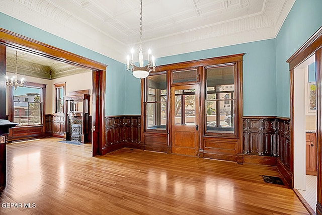 unfurnished room with a healthy amount of sunlight, a notable chandelier, and hardwood / wood-style floors