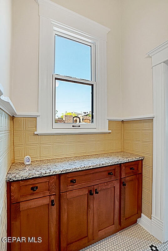 kitchen with light stone countertops, backsplash, and light tile floors