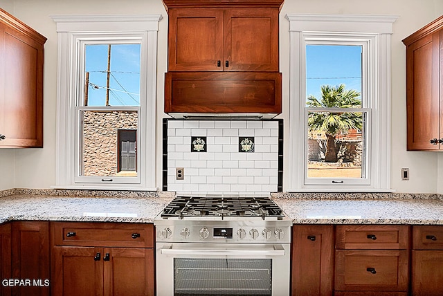 kitchen featuring light stone counters, backsplash, and stainless steel stove