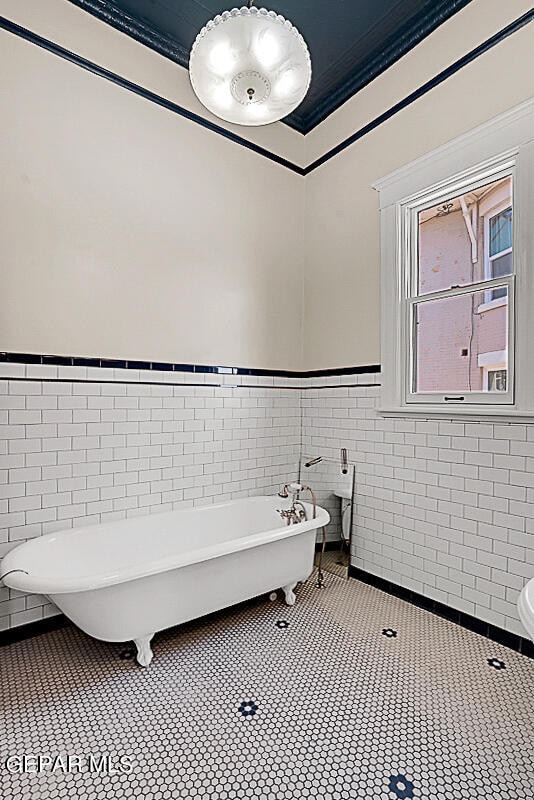 bathroom featuring tile flooring, tile walls, a bath, and ornamental molding