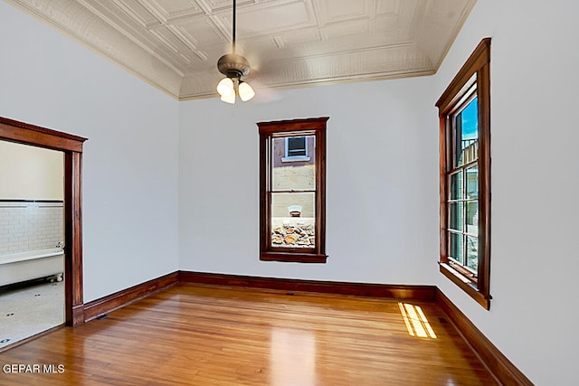 unfurnished room with a wealth of natural light, ornamental molding, wood-type flooring, and ceiling fan