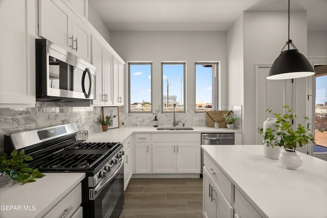 kitchen with hanging light fixtures, white cabinetry, sink, and stainless steel appliances