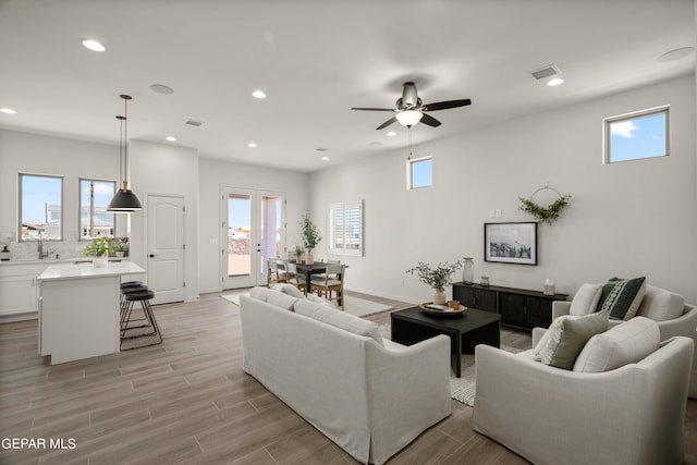 living room featuring light hardwood / wood-style flooring, ceiling fan, and a healthy amount of sunlight