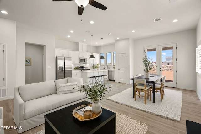 living room featuring french doors, light hardwood / wood-style floors, and ceiling fan