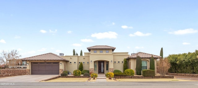 mediterranean / spanish-style home featuring a tile roof, driveway, an attached garage, and stucco siding