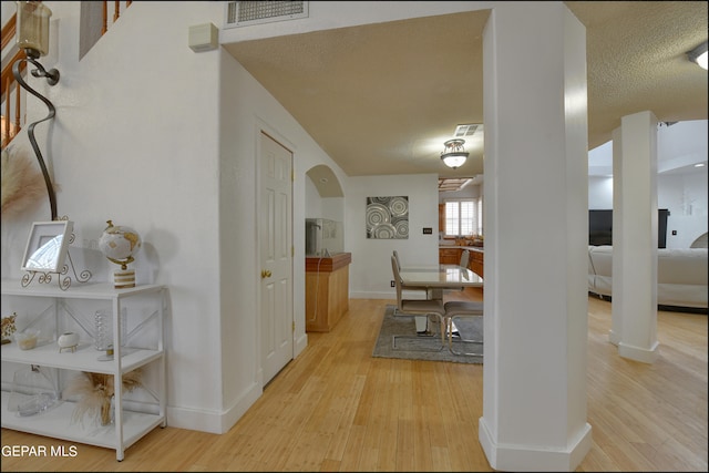 hall featuring light hardwood / wood-style flooring and a textured ceiling