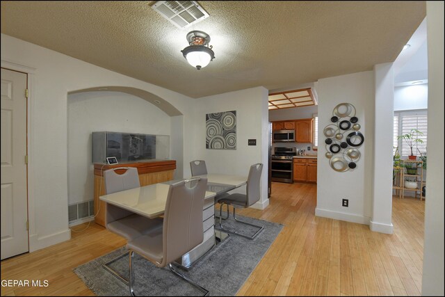 dining space with light wood-type flooring and a textured ceiling