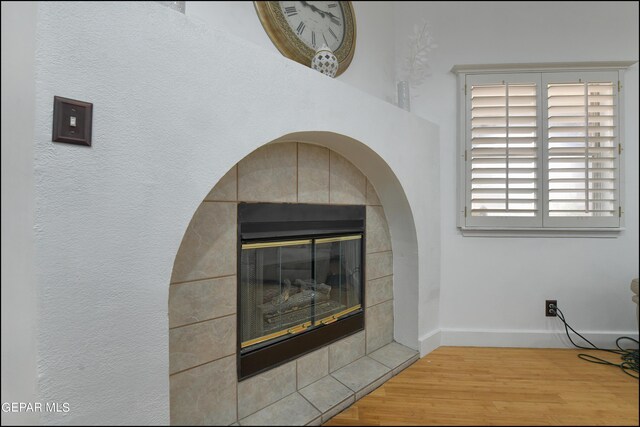 room details with a tiled fireplace and hardwood / wood-style floors