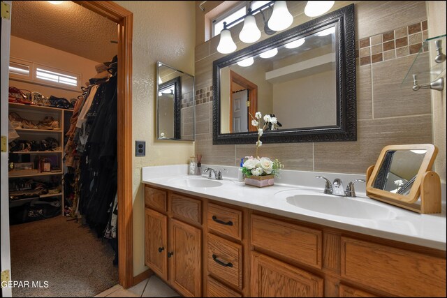 bathroom with tile patterned flooring, dual vanity, a shower, and a wealth of natural light