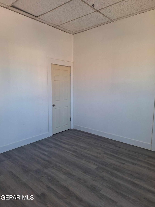 unfurnished room featuring dark wood-type flooring and a drop ceiling