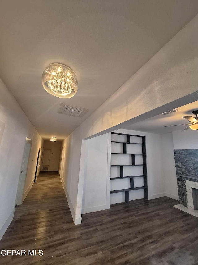 interior space with built in shelves, dark hardwood / wood-style flooring, and ceiling fan with notable chandelier