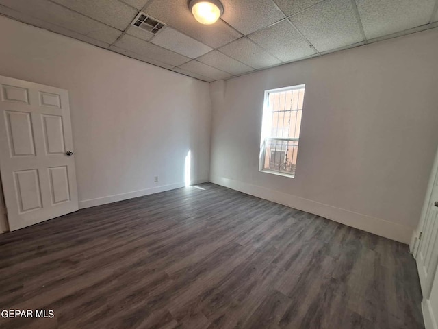 spare room featuring dark wood-type flooring and a drop ceiling