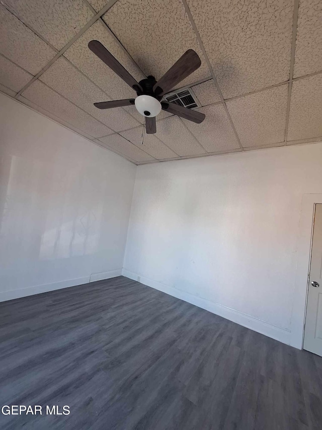 empty room with a drop ceiling, ceiling fan, and dark hardwood / wood-style flooring