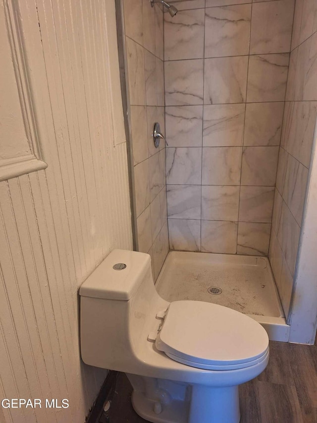 bathroom featuring a tile shower, toilet, and hardwood / wood-style flooring