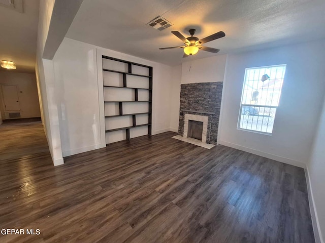 unfurnished living room with a textured ceiling, ceiling fan, dark hardwood / wood-style floors, and a fireplace