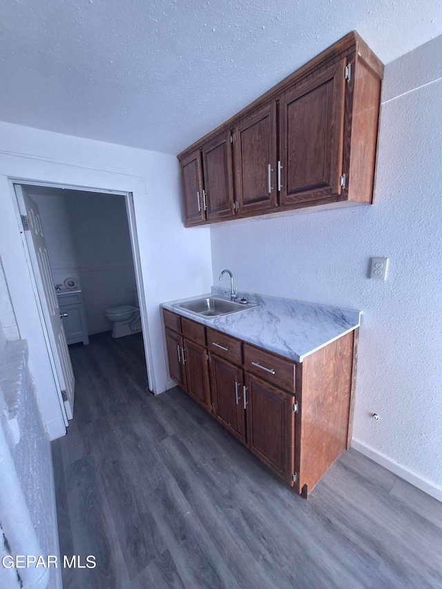 kitchen featuring sink, light stone countertops, a textured ceiling, and dark hardwood / wood-style floors