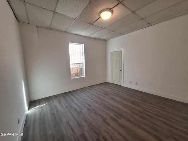 empty room featuring a paneled ceiling and dark hardwood / wood-style floors