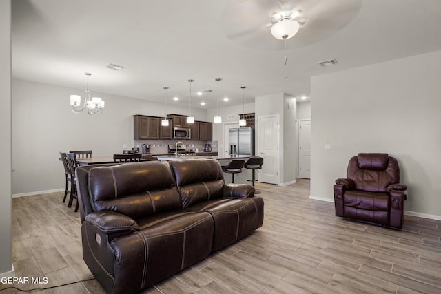 living room with ceiling fan with notable chandelier and sink