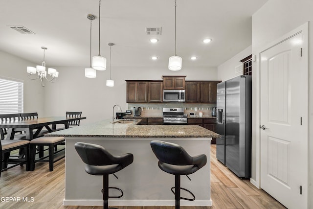 kitchen with pendant lighting, sink, decorative backsplash, dark brown cabinetry, and stainless steel appliances