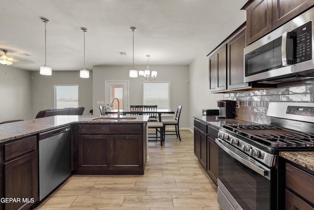 kitchen featuring appliances with stainless steel finishes, dark brown cabinetry, pendant lighting, and sink