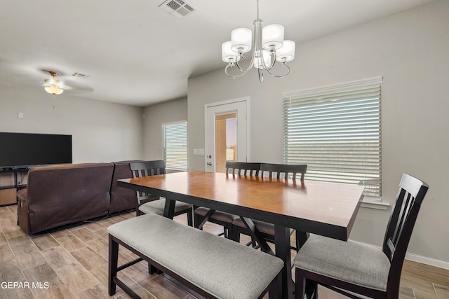 dining space featuring ceiling fan with notable chandelier