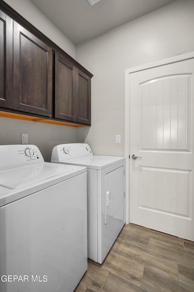 laundry room with cabinets, washer and dryer, and light hardwood / wood-style floors