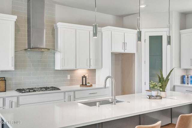 kitchen featuring sink, wall chimney exhaust hood, tasteful backsplash, and stainless steel gas cooktop