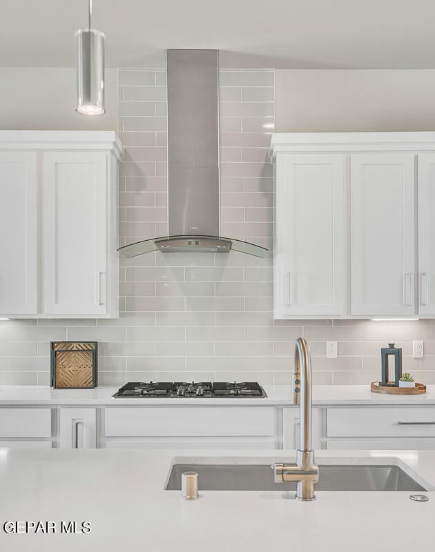 kitchen with backsplash, white cabinets, wall chimney exhaust hood, and stainless steel gas cooktop