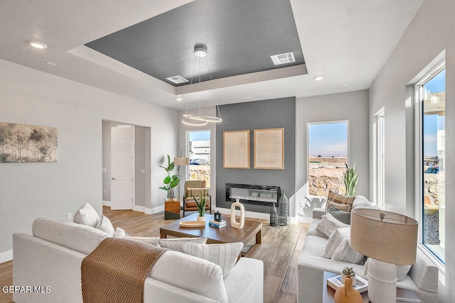 living room with a tray ceiling and light hardwood / wood-style floors